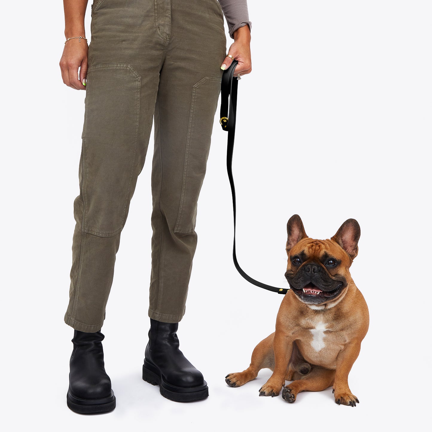 human holding black trill paws leash attached to french bulldog
